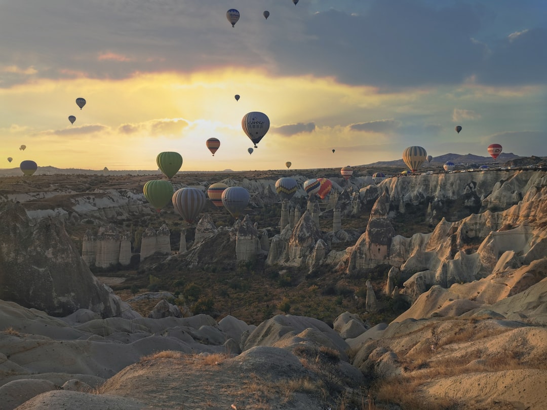 hot air balloons floating over rocky mountains during sunset