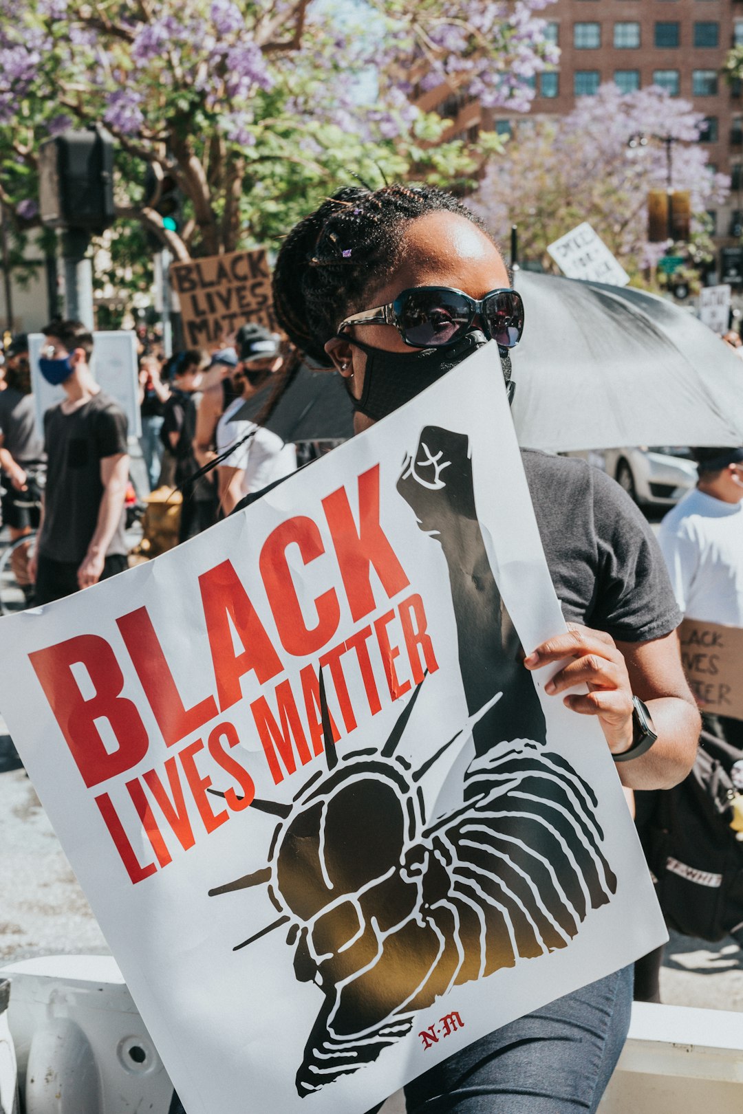 man in black sunglasses holding white and red love me print banner