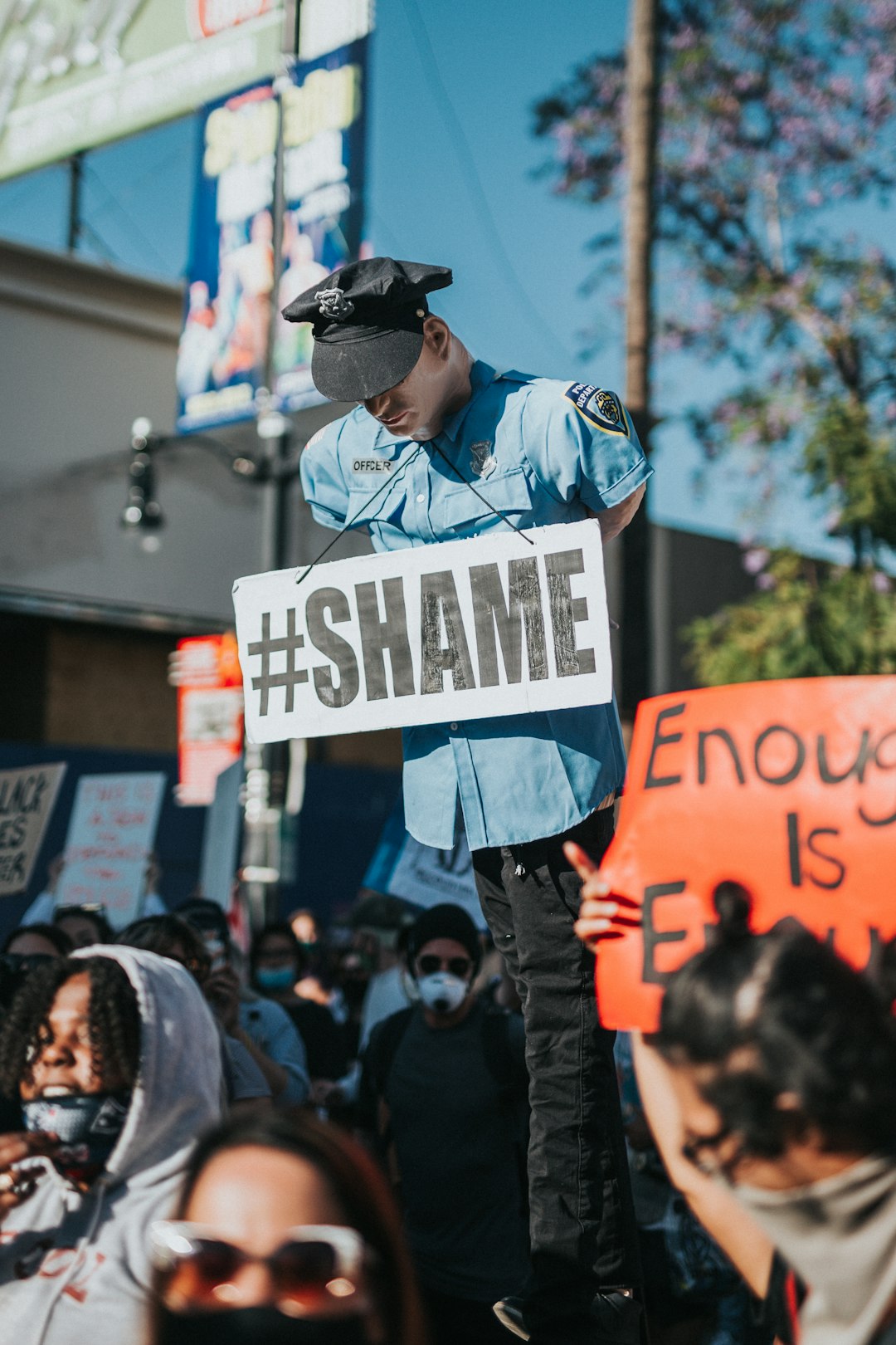 man in blue denim jacket and black hat holding white and black signage