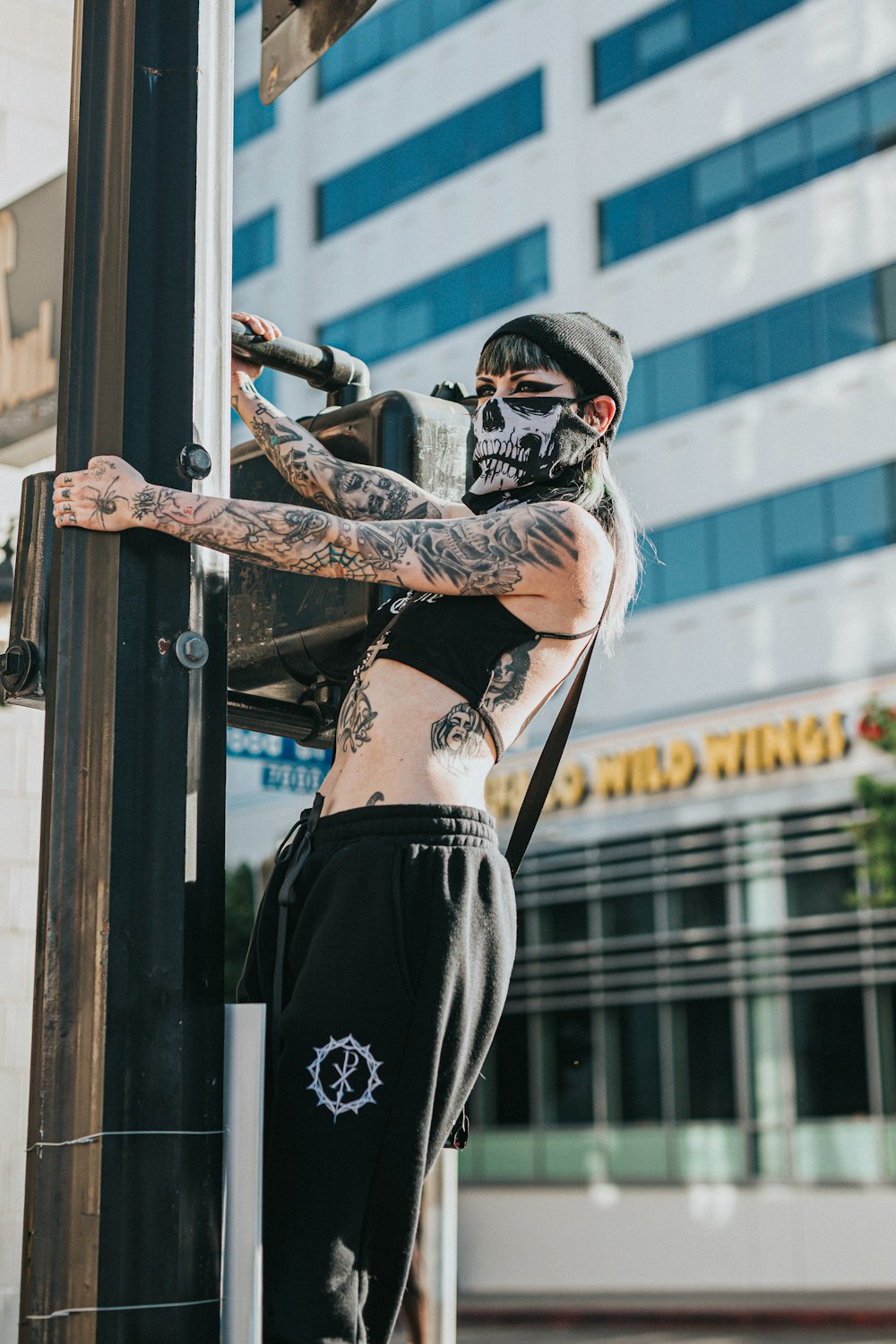 woman in black crop top and black skirt standing beside glass window during daytime