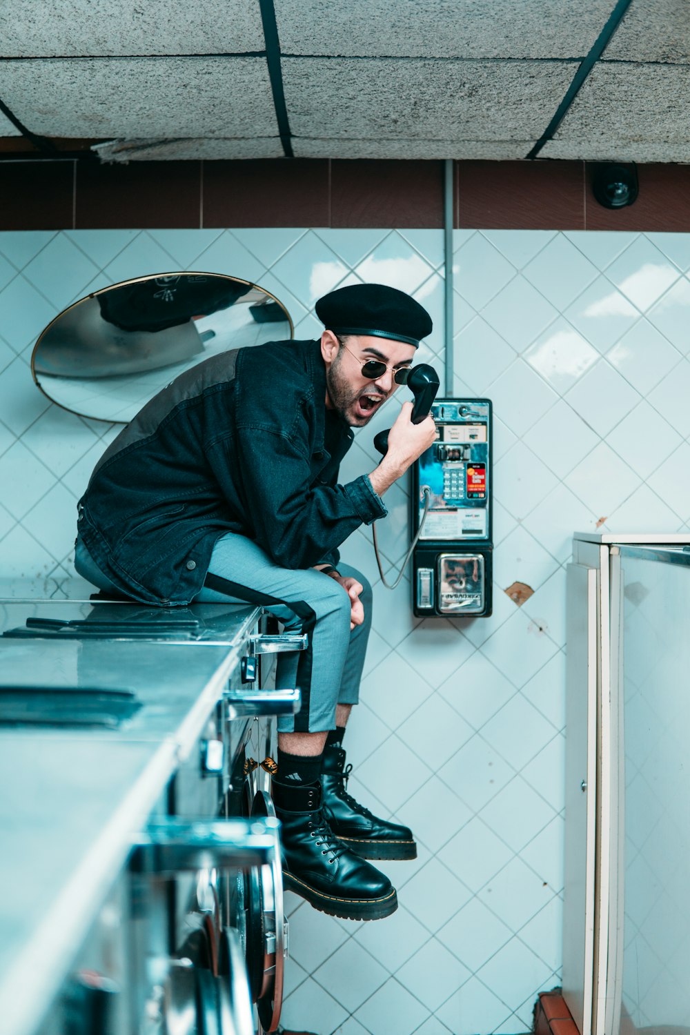 man in blue jacket and black cap holding black smartphone