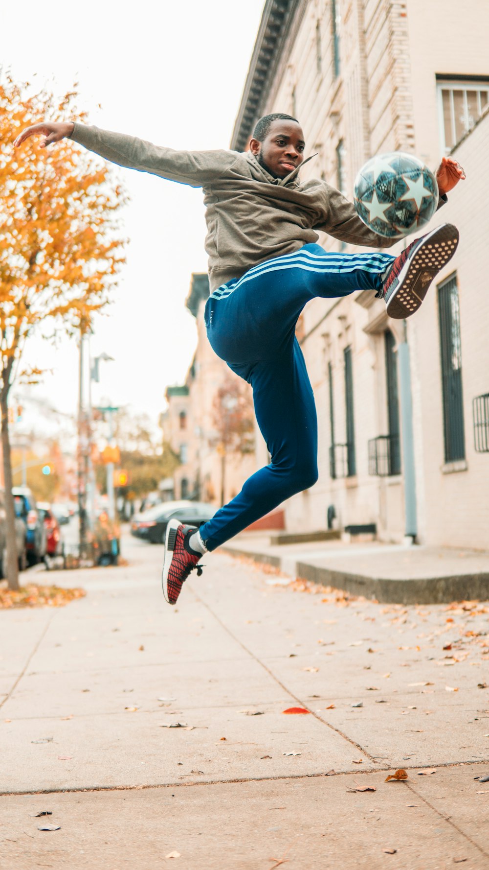 man in gray shirt and blue denim jeans jumping on brown concrete floor during daytime