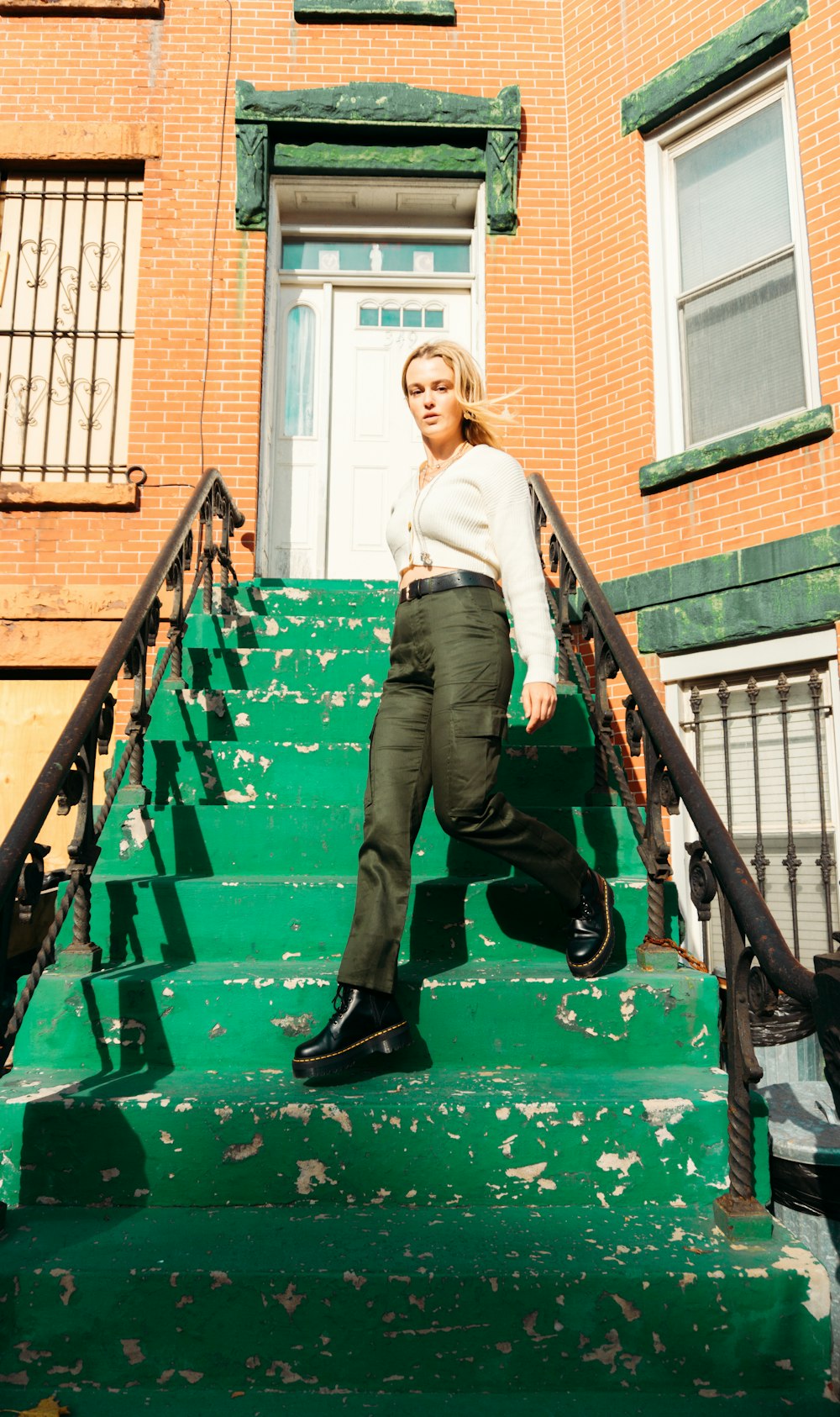 woman in gray long sleeve shirt and black pants sitting on green concrete staircase