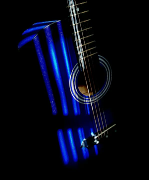 Close-up of a guitar with shadowy blue tones under soft light.