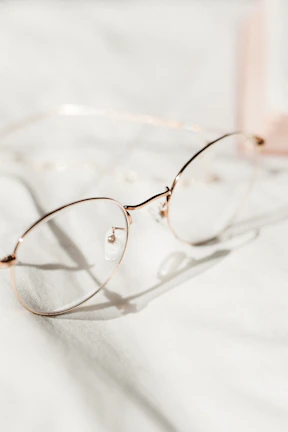 A stylish pair of amber-colored glasses displayed on a marble surface with soft natural light.