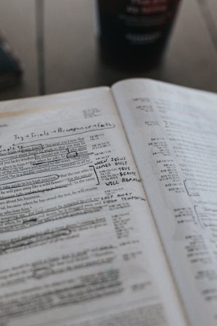 Close-up of hands holding an open Bible with notes and highlights, symbolizing study and reflection.