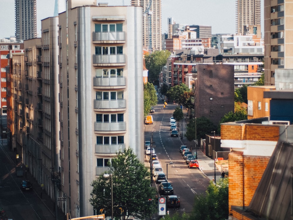 cars parked on the side of the road near high rise buildings during daytime