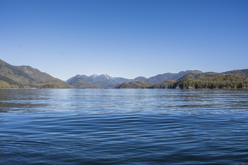 mar azul perto da montanha sob o céu azul durante o dia