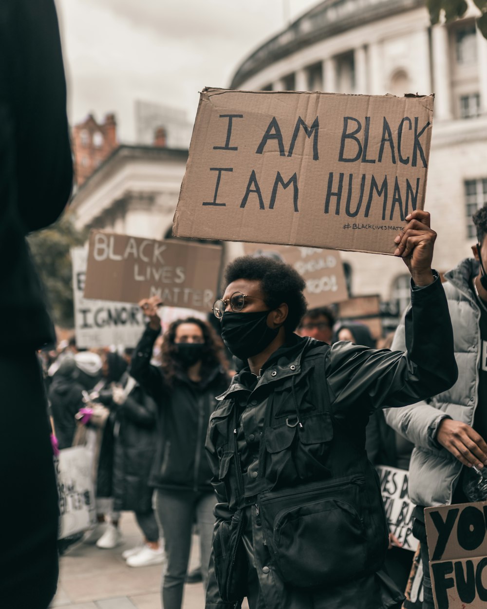 man in black leather jacket holding brown wooden board