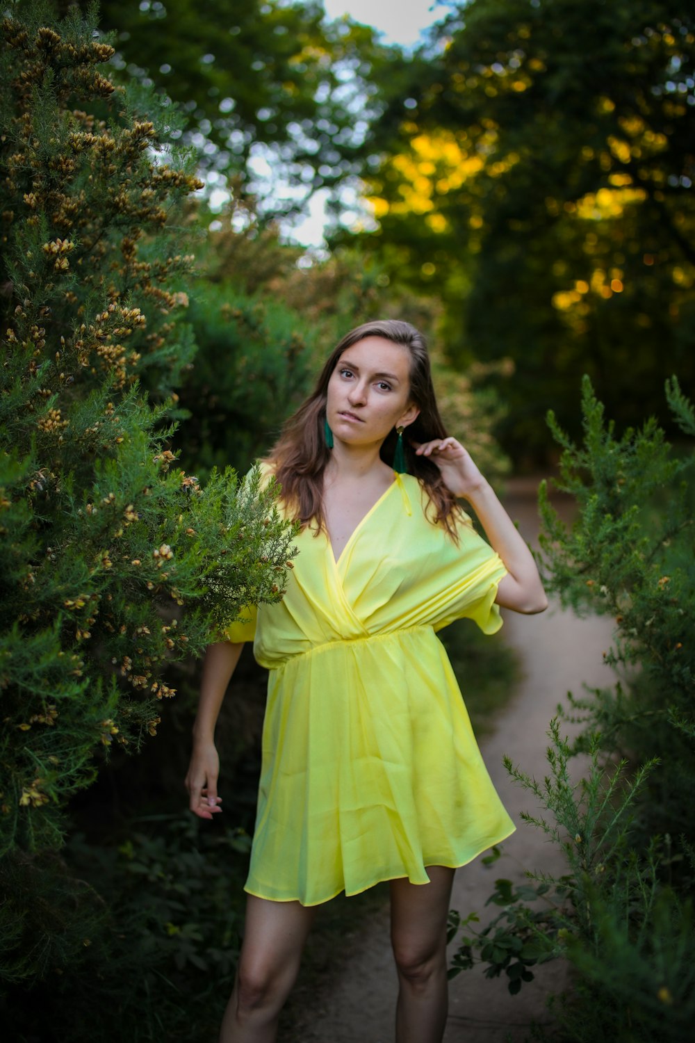 woman in yellow sleeveless dress standing beside green plant during daytime
