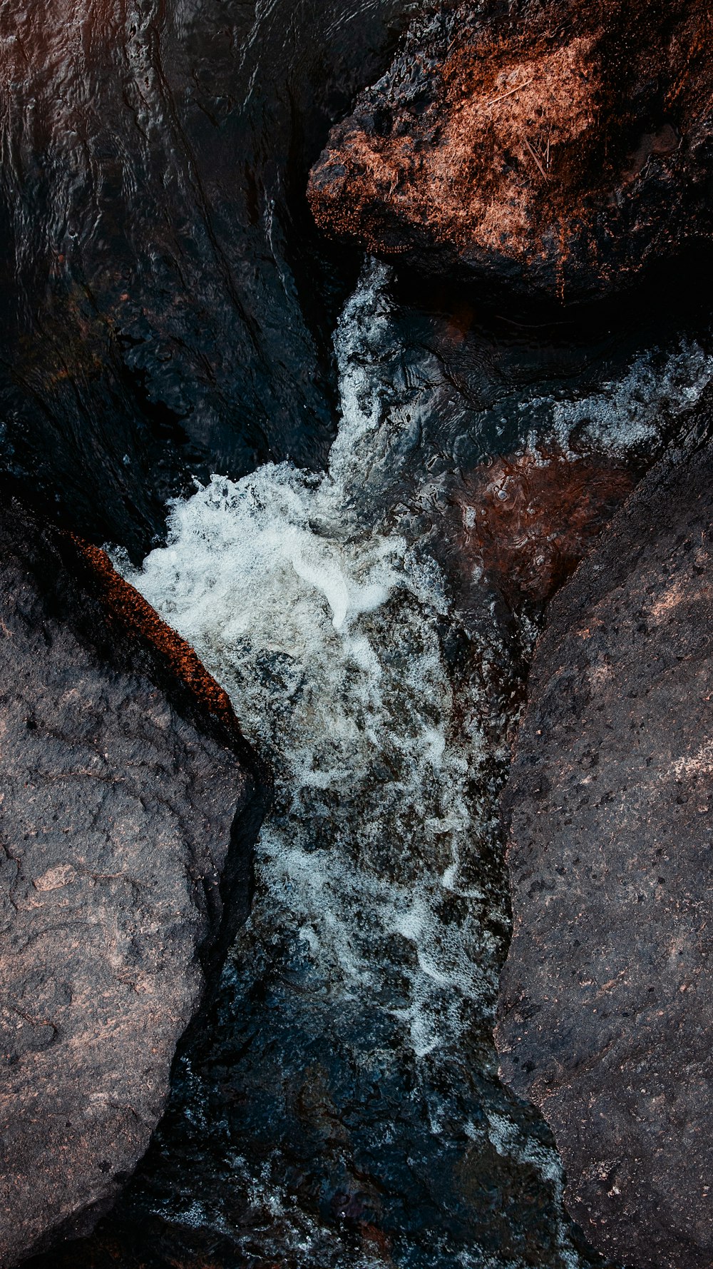 water falls on rocky shore during daytime