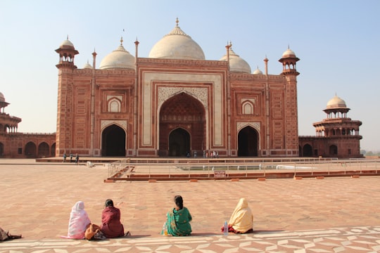 people walking on brown sand near brown concrete building during daytime in Taj Mahal India