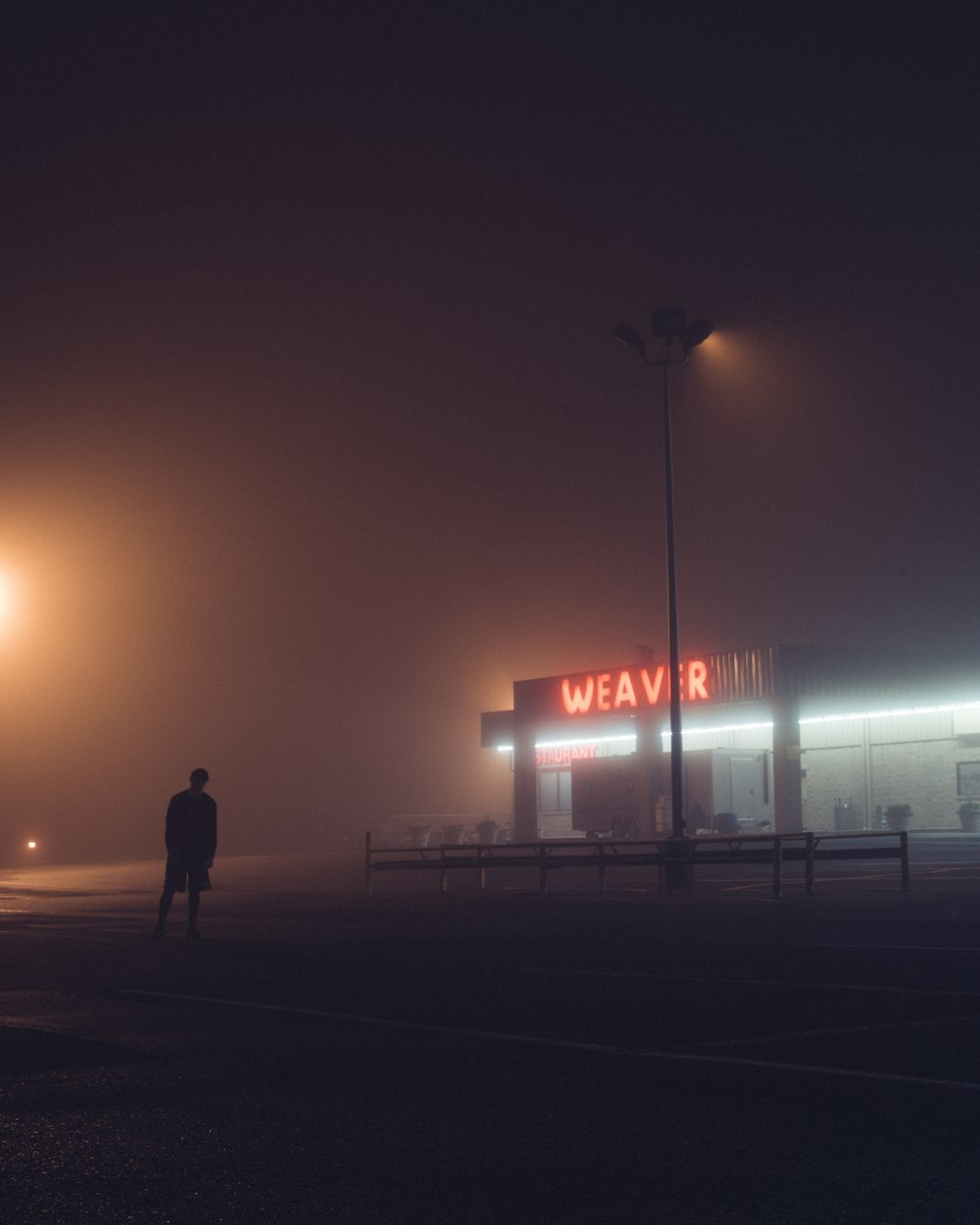 Un hombre parado frente a un edificio en una noche de niebla