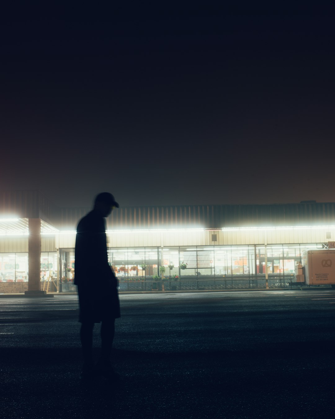 silhouette of person standing on road during sunset