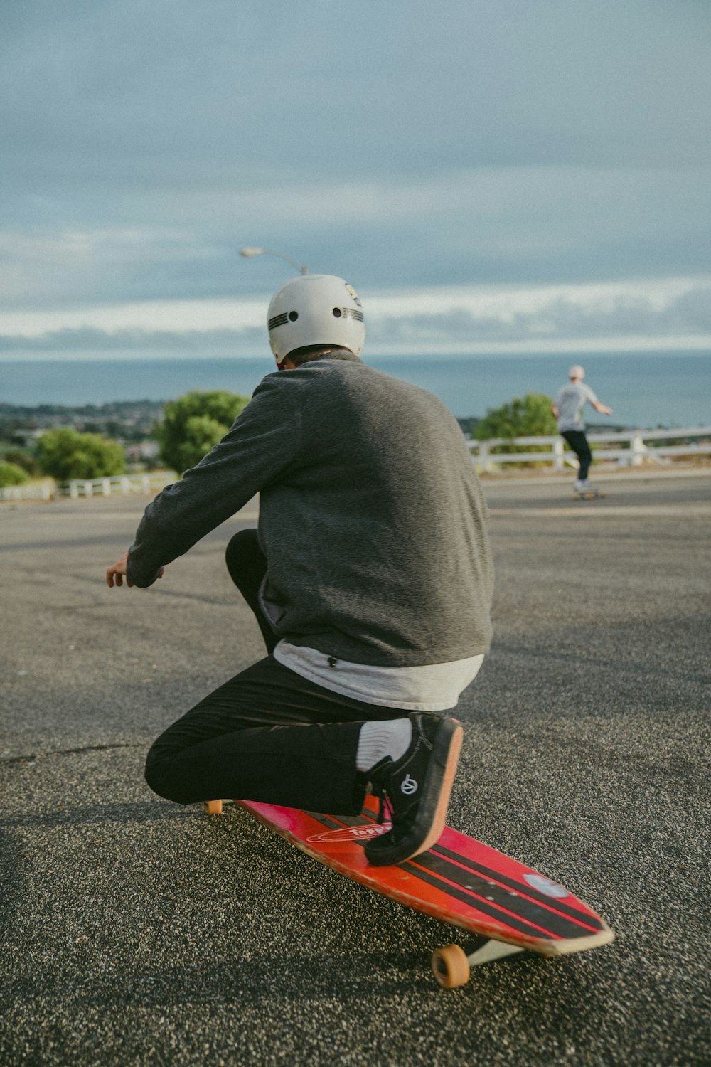 man in gray hoodie and black pants riding red skateboard during daytime