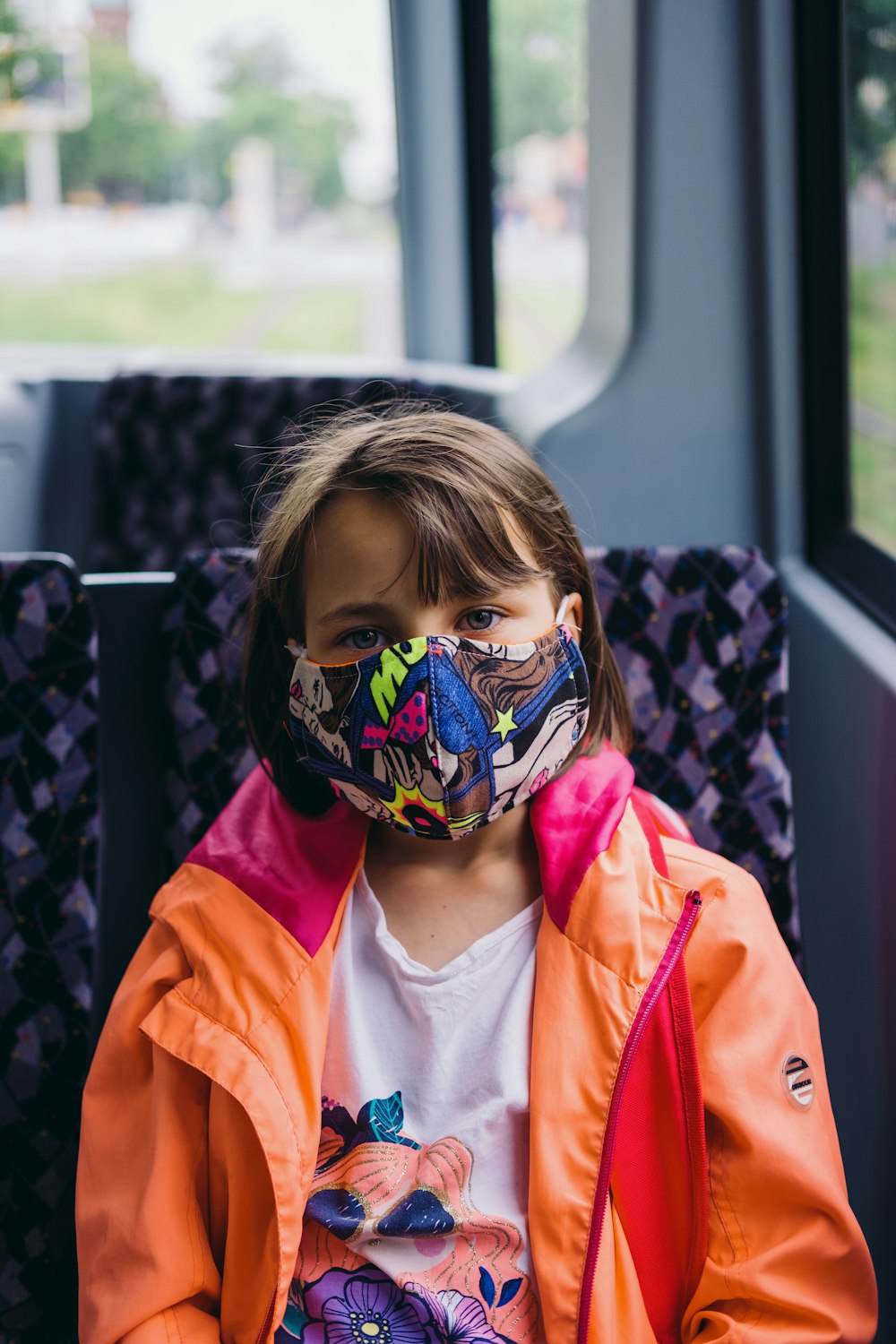 girl in orange jacket wearing blue mask