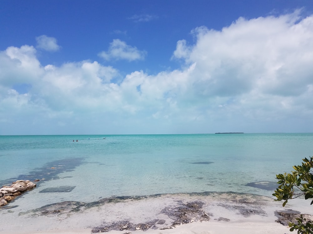 a sandy beach with clear blue water under a cloudy sky