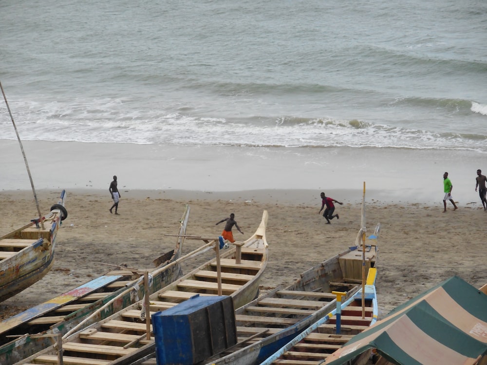 a group of people walking along a beach next to boats