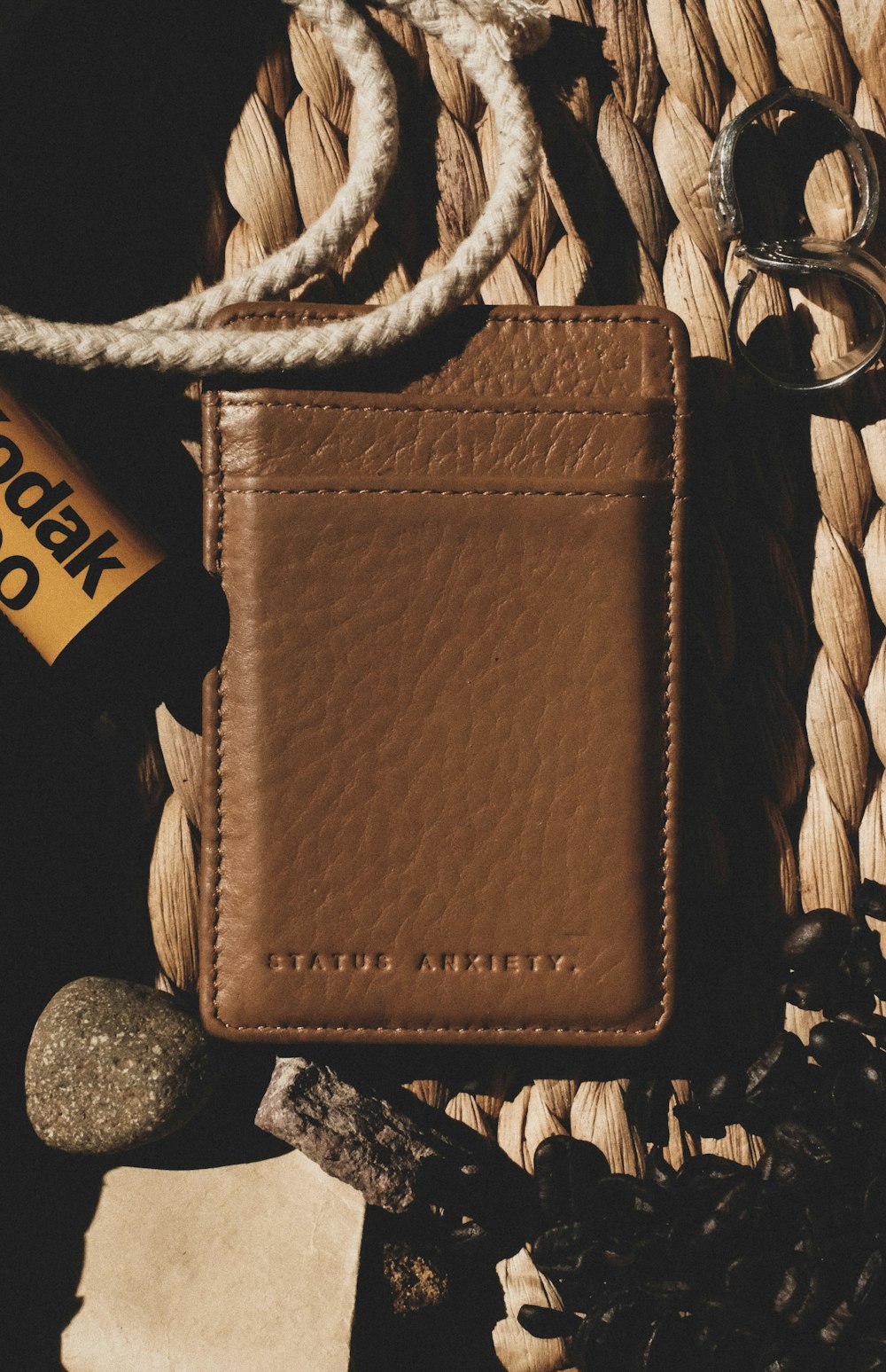 brown leather bifold wallet on black and gray stones