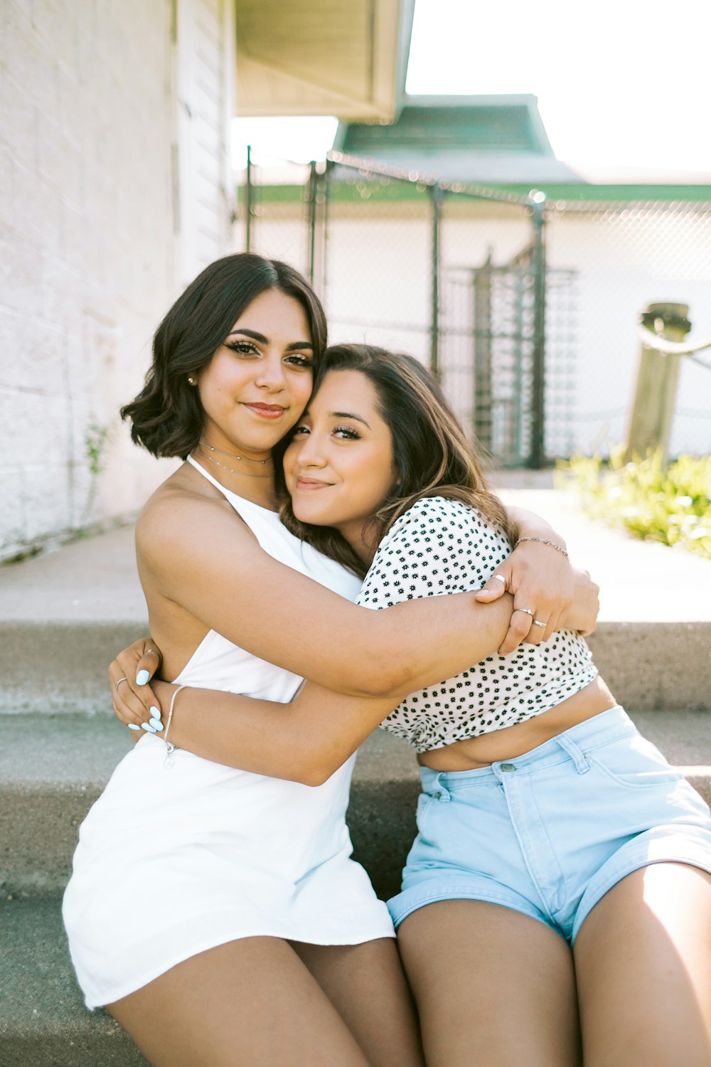 woman in white and black polka dot tank top and blue denim shorts hugging woman in during