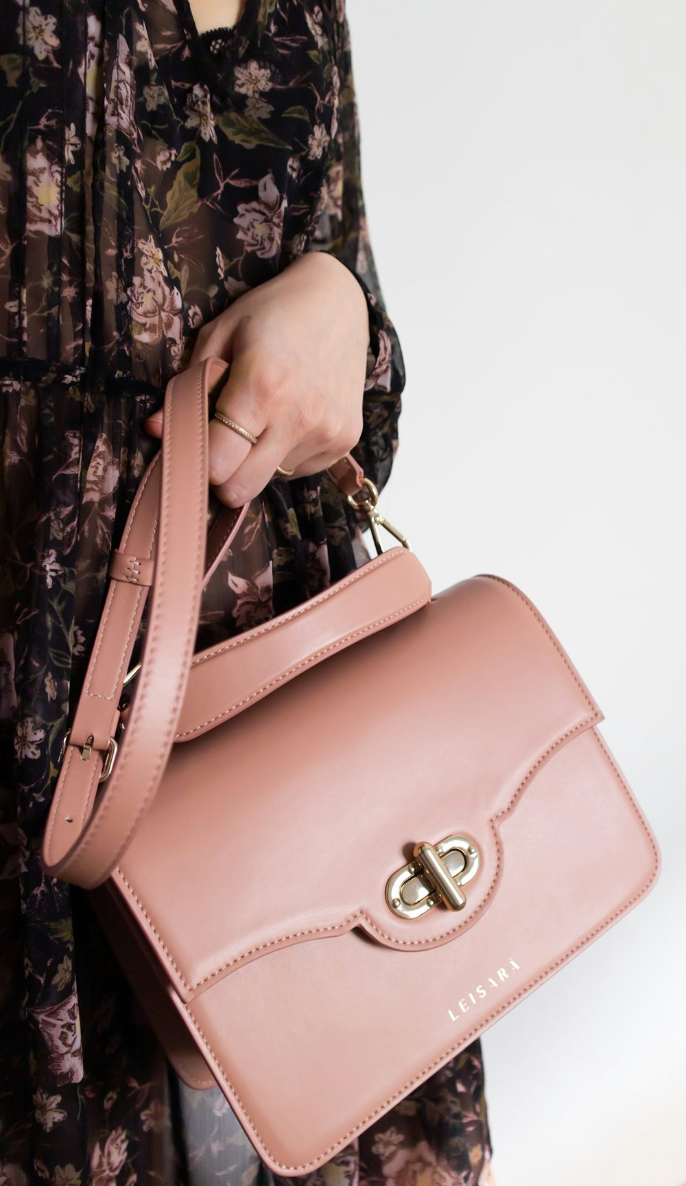 woman holding brown leather sling bag