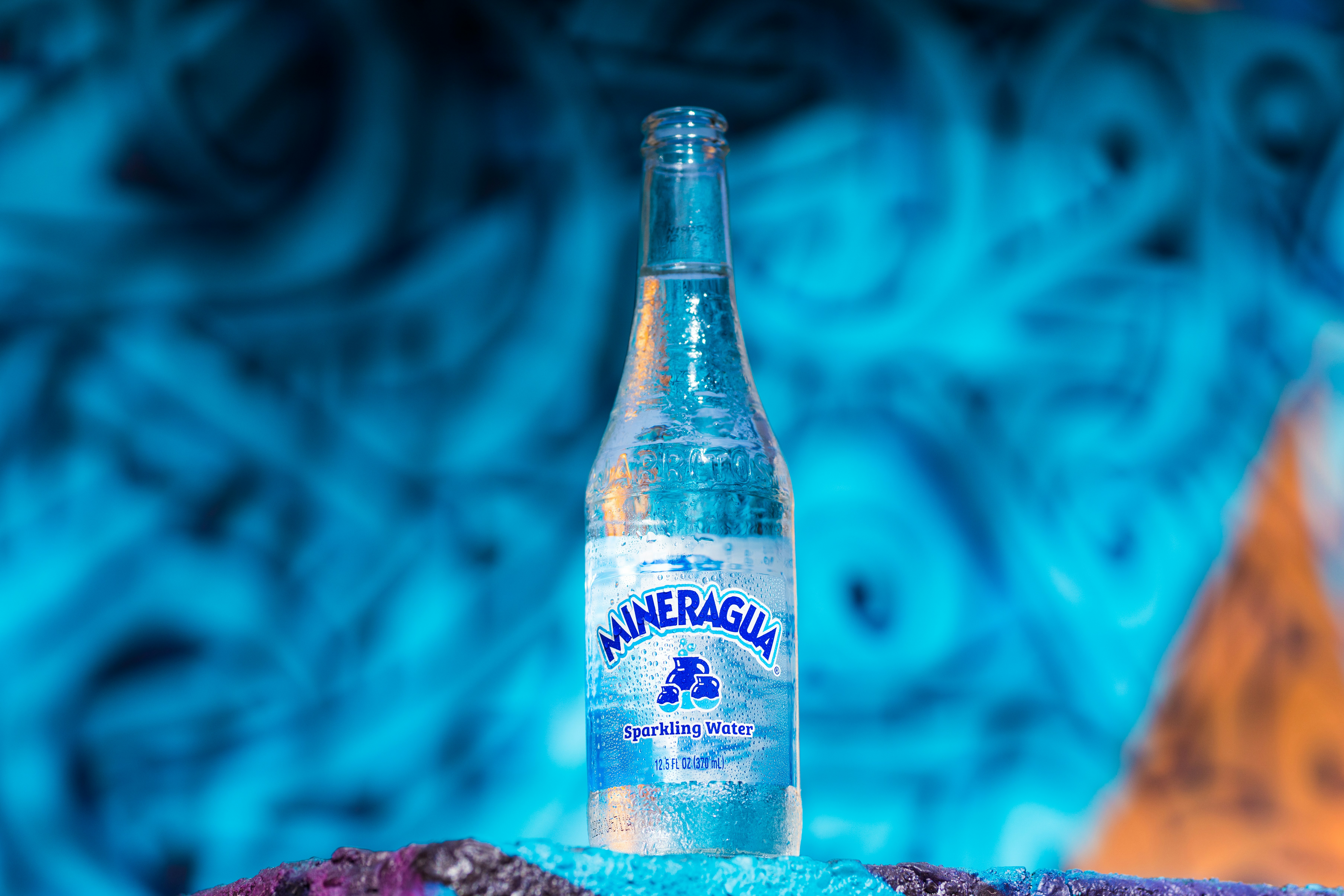 Clear sparkling water bottle with bubbles on light blue background