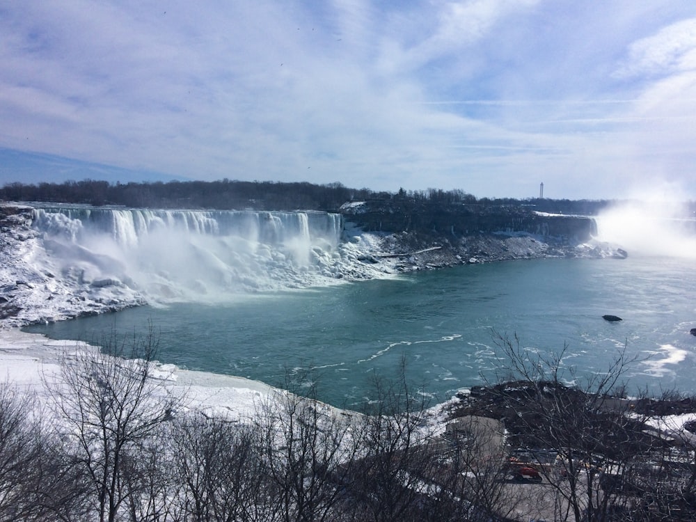 water falls under blue sky during daytime