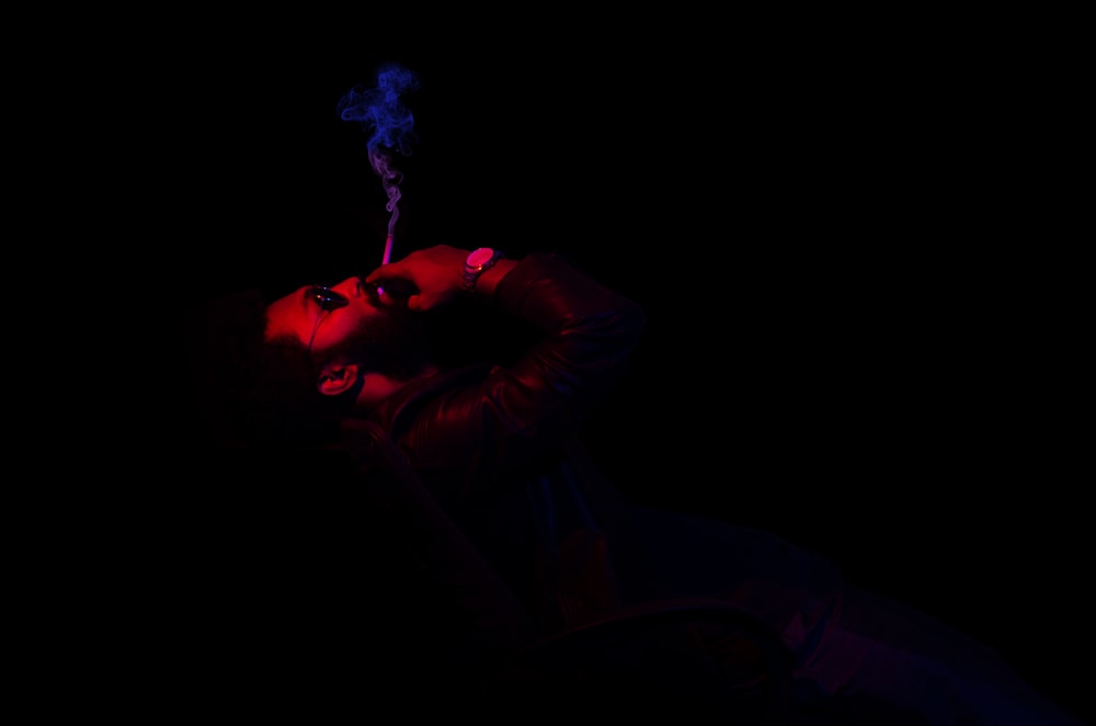 man in black long sleeve shirt holding blue smoke