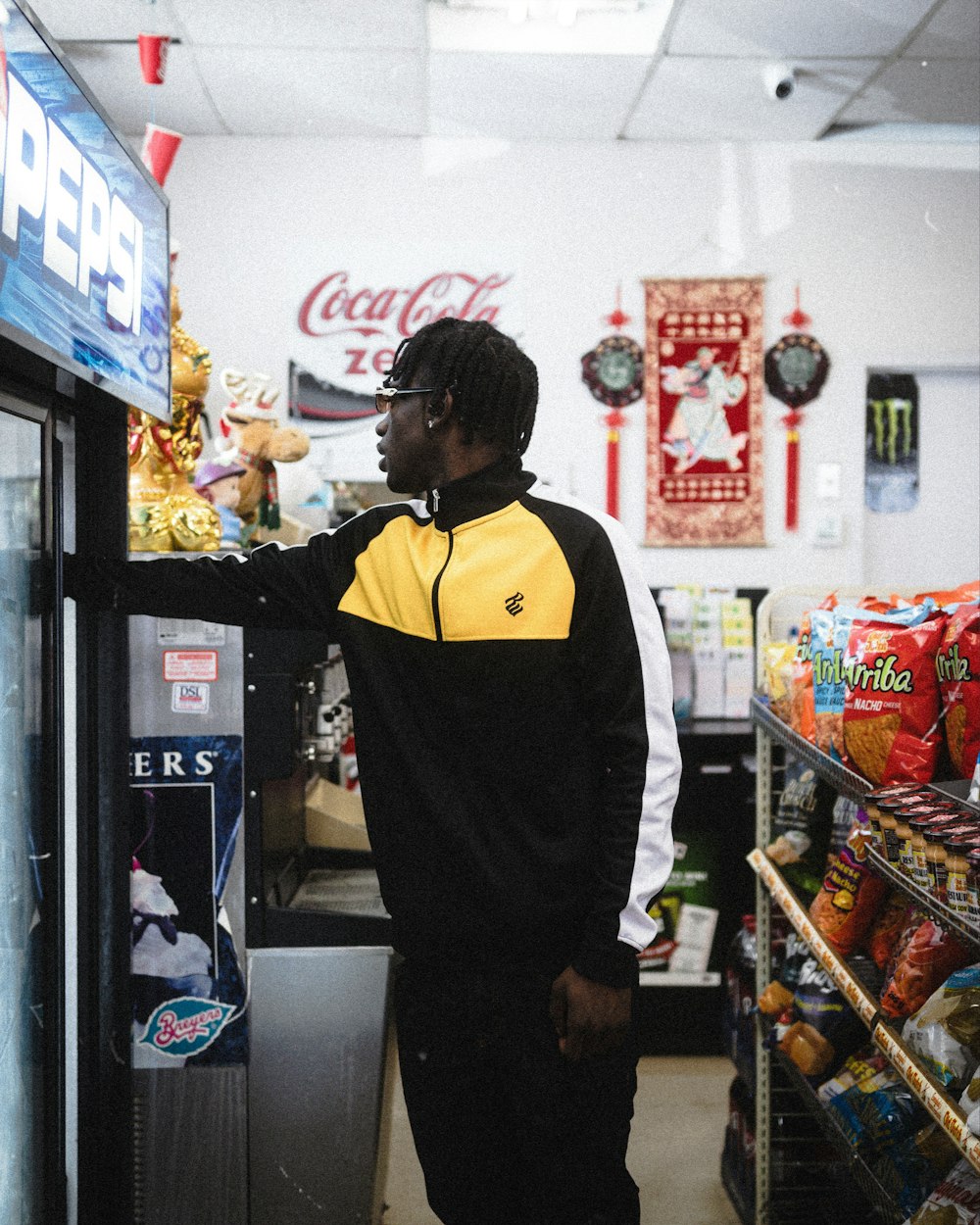 man in black and yellow jacket standing near food display counter