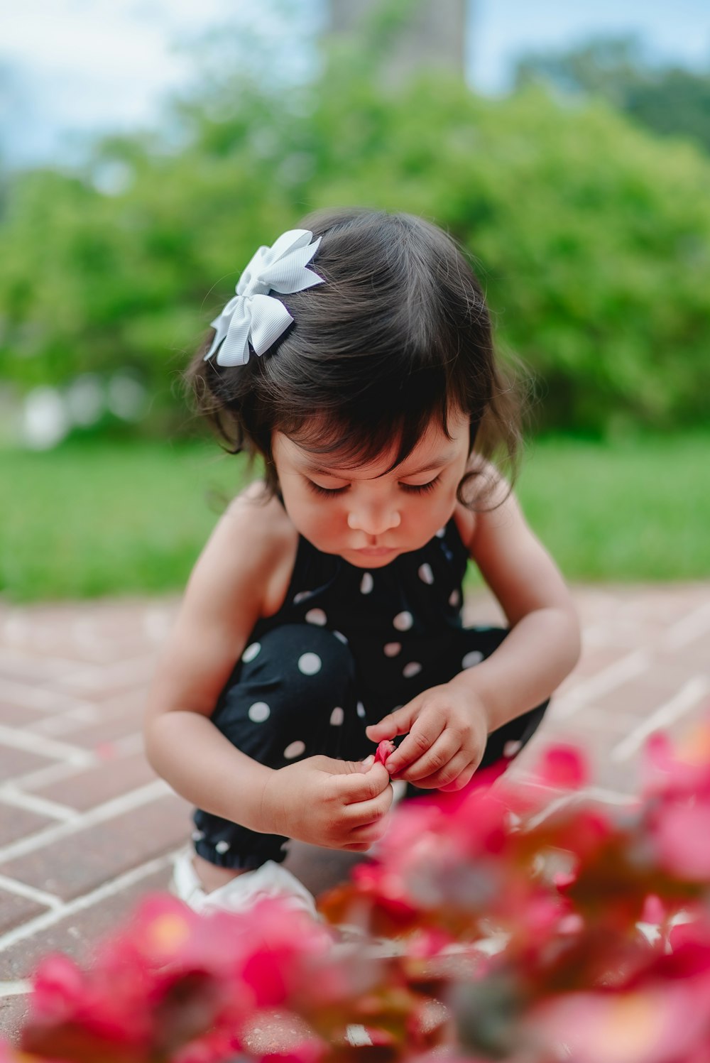 girl in black and white polka dot dress sitting on concrete floor during daytime