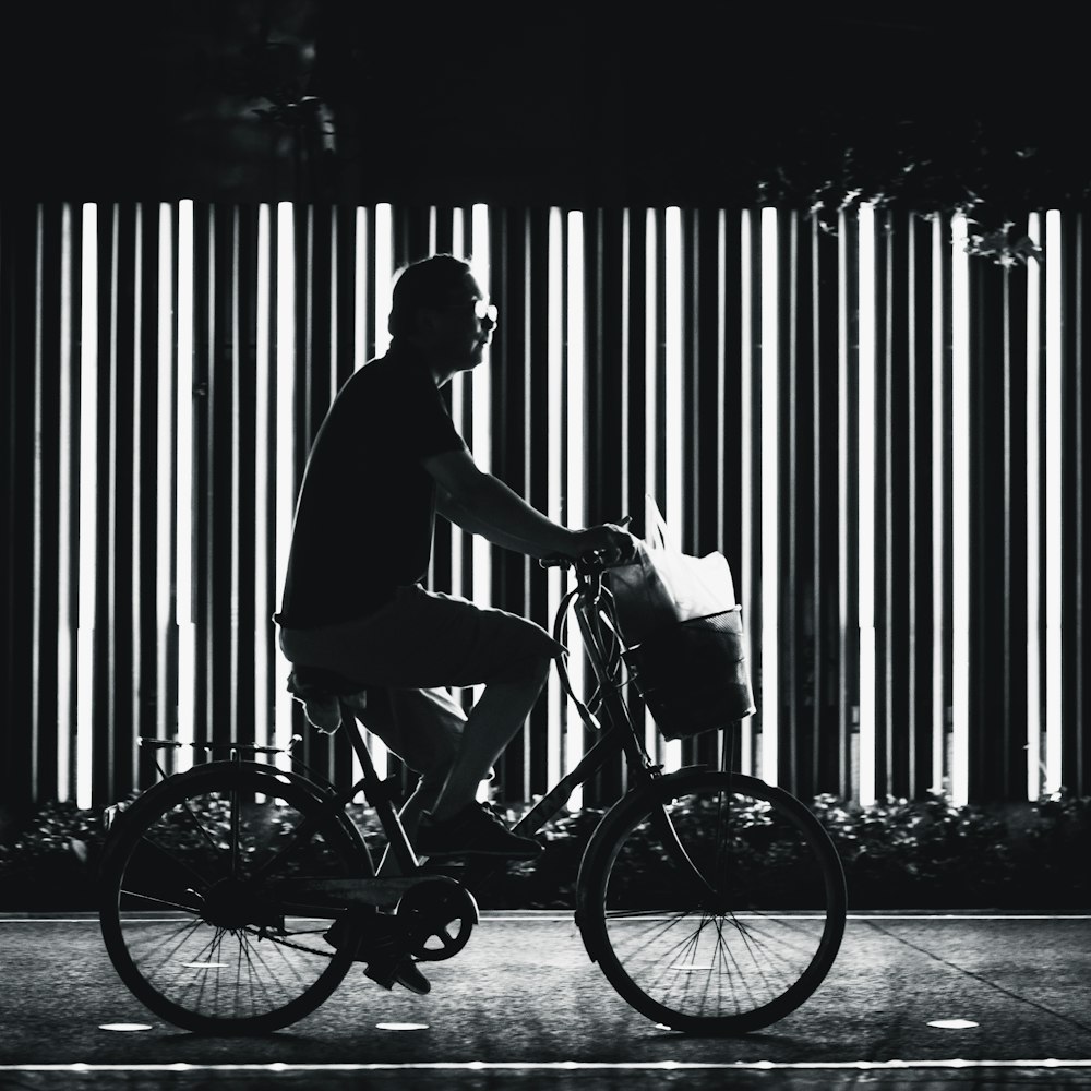 man riding on bicycle in grayscale photography