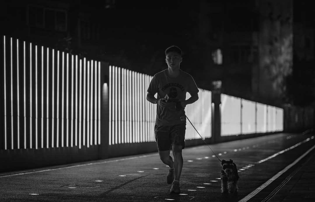 man in black crew neck t-shirt and black pants holding black dog leash