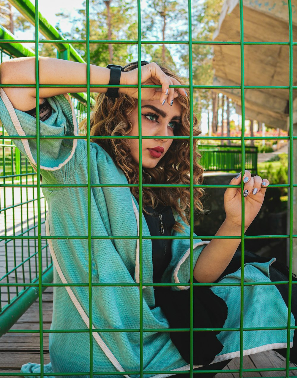 woman in blue shirt holding green metal fence