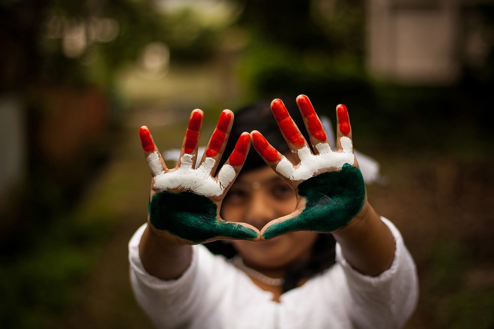 person in white shirt with green paint on hand