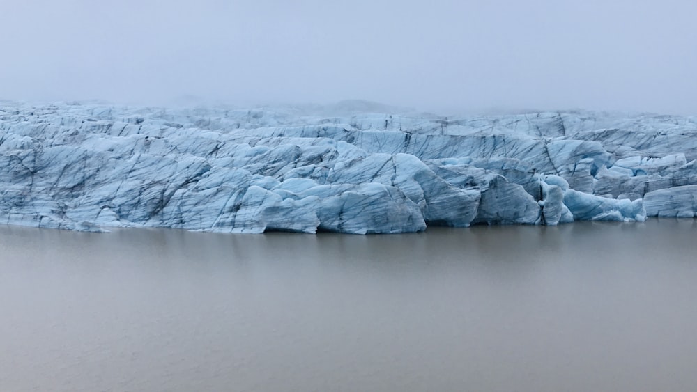 white snow covered mountain beside body of water