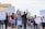 A diverse group of people is marching, holding various protest signs that call for justice and change. Many demonstrators have raised fists, indicating solidarity and determination. The participants are dressed casually and some wear masks. The setting appears to be an urban street.