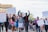 A diverse group of people is marching, holding various protest signs that call for justice and change. Many demonstrators have raised fists, indicating solidarity and determination. The participants are dressed casually and some wear masks. The setting appears to be an urban street.
