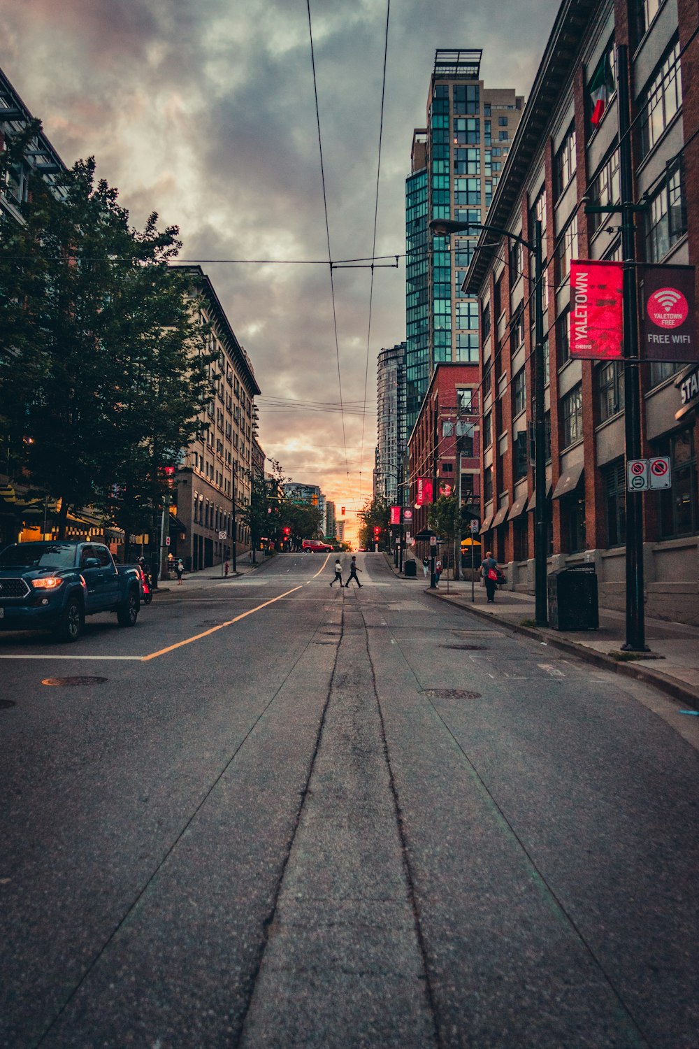 cars parked on side of the road in between high rise buildings during daytime