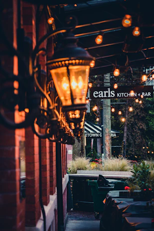 An inviting patio scene featuring hanging lanterns softly glowing at dusk among lush artificial green plants.