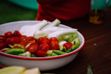 A ceramic mixing bowl filled with fresh vegetables ready to chop.