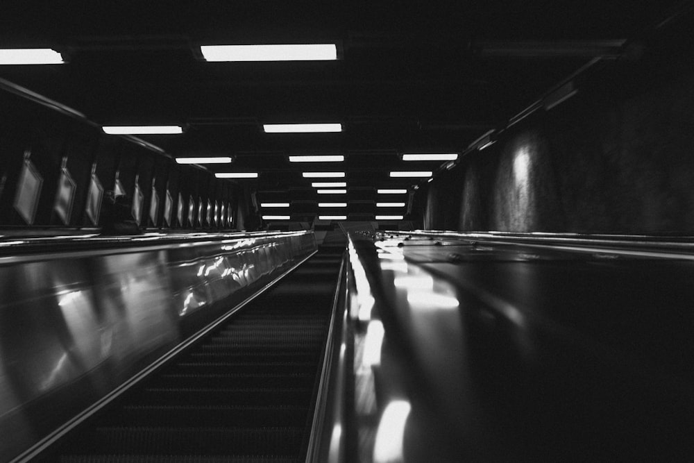 grayscale photo of escalator in tunnel