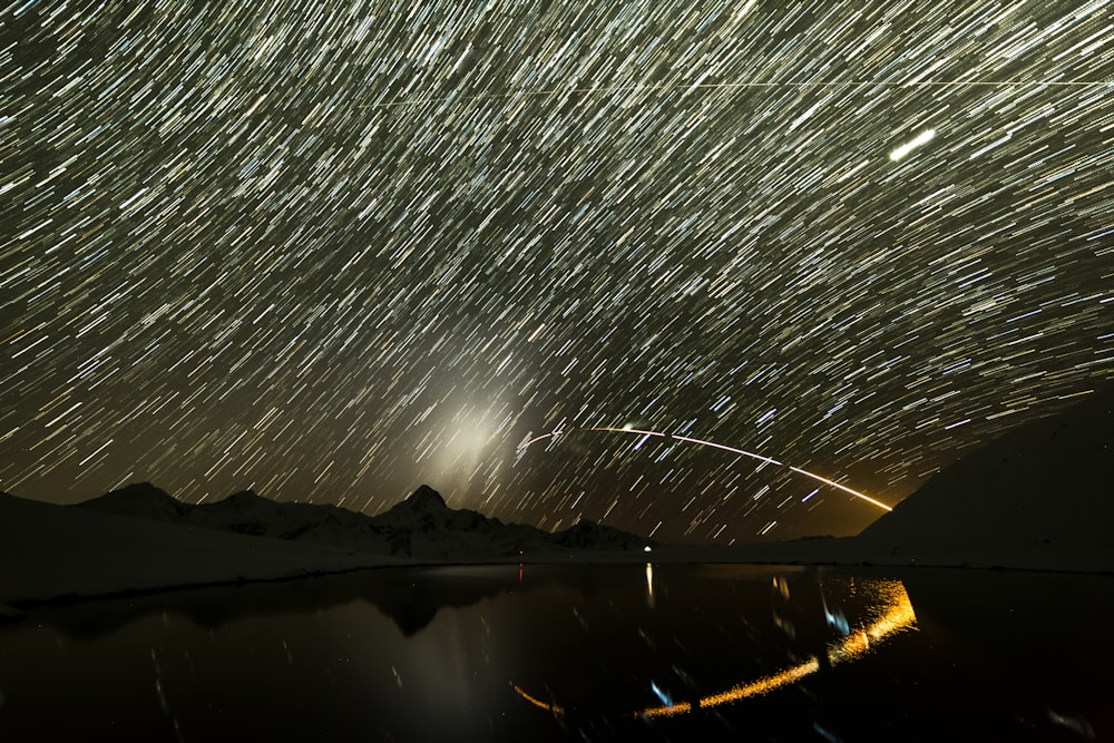 body of water near mountain during night time