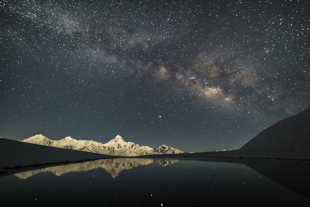 body of water near mountain under starry night