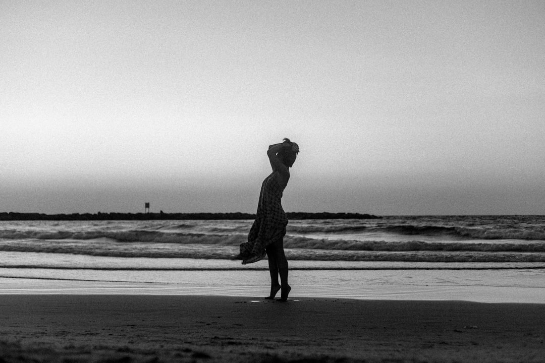 grayscale photo of man walking on beach