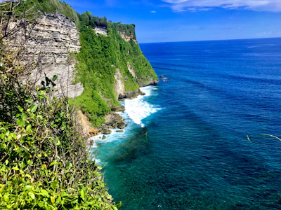 A panoramic view of São Jorge's lush green cliffs meeting the Atlantic Ocean under a clear blue sky