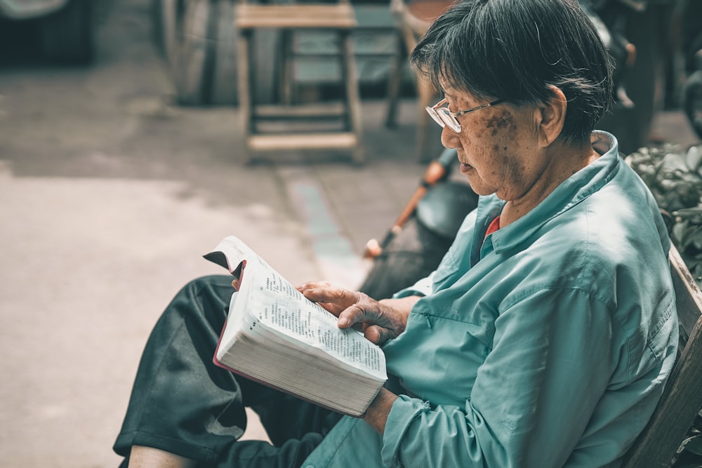 man in teal dress shirt reading book