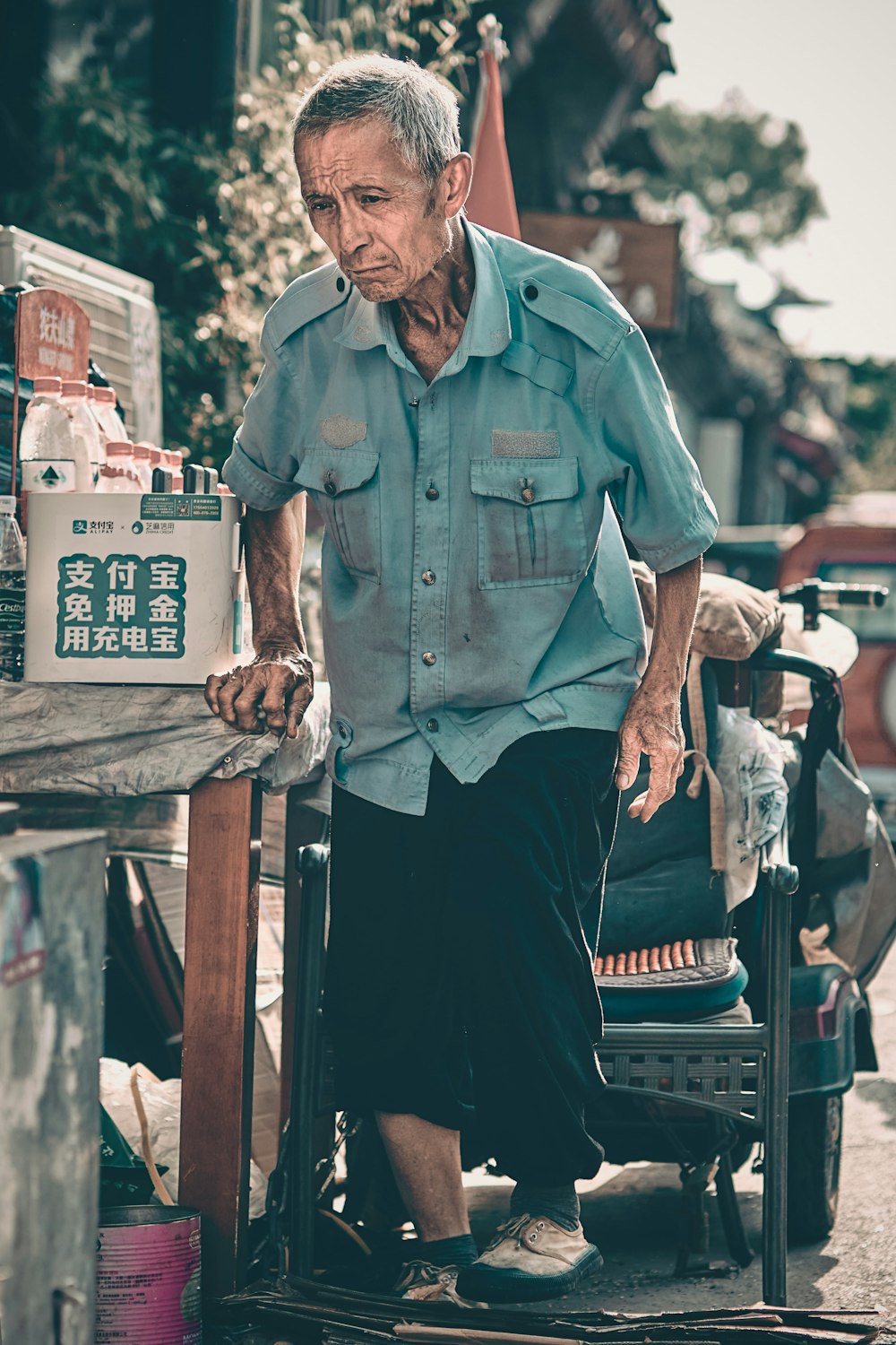 man in blue button up shirt and black pants sitting on brown wooden bench