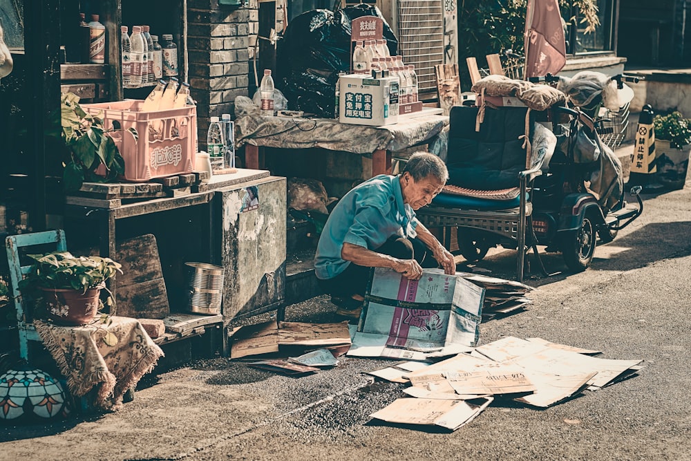 hombre en camiseta azul sentado en la silla leyendo el periódico