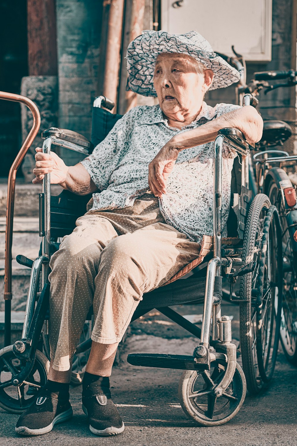 homme en chemise boutonnée bleue et blanche assis sur un fauteuil roulant noir