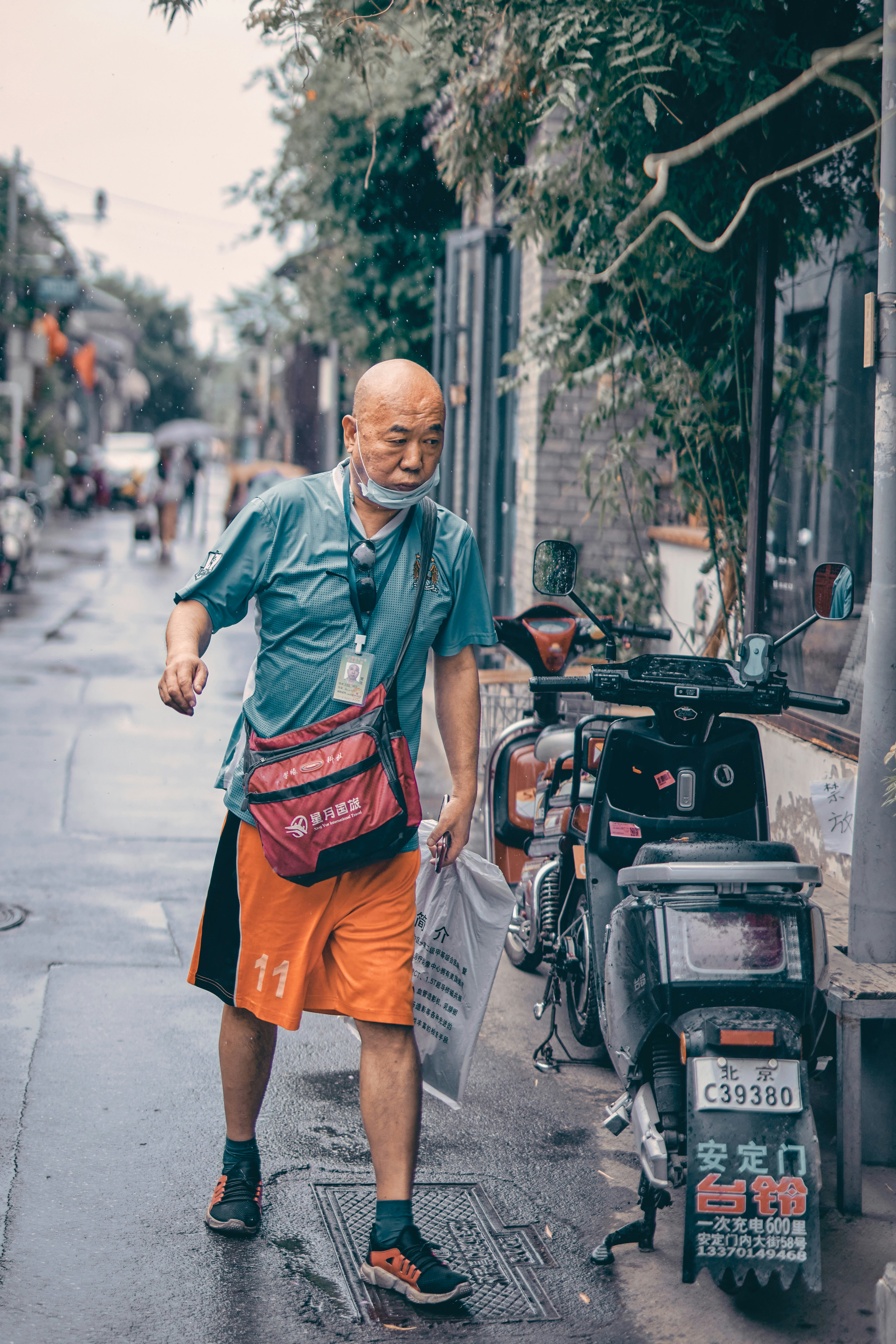 man in green polo shirt and red shorts standing on sidewalk during daytime